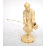 A Japanese Ivory Okimono, Meiji period, as a fisherman holding a rod and putting a fish into a