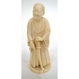 A Japanese Ivory Okimono, Meiji period, as a dignitary standing in flowing robes holding a sword, on