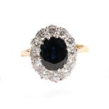 An 18 Carat Gold Sapphire and Diamond Cluster Ring, an oval cut sapphire within a border of round