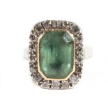 An Emerald and Diamond Ring, an octagonal cut emerald in a closed backed grain setting and within