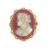 A Sardonyx Cameo Brooch, Carved Depicting a Classical Female Bust, in a scroll frame, measures 3.8cm