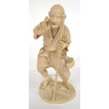 A Japanese Ivory Okimono, Meiji period, as an elderly man standing leaning on a bamboo cane, on an