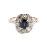 A Sapphire and Diamond Cluster Ring, an oval cut sapphire within a border of old cut diamonds, total