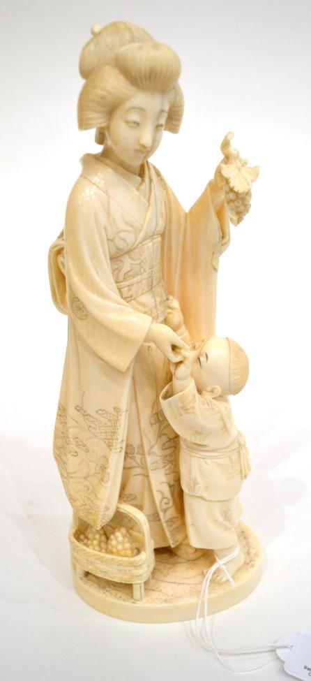 A Japanese Ivory Okimono, Meiji period, as a mother and child, she holding a bunch of grapes, a