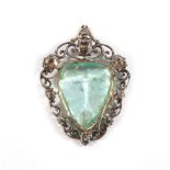 An Emerald and Diamond Pendant, a trilliant mixed cut emerald in a collet setting within a scroll