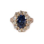 A Synthetic Sapphire and Diamond Cluster Ring, an oval cut synthetic sapphire in a claw setting,