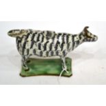 A Pearlware Cow Creamer and Stopper, circa 1810, with black and white striped markings, on a green