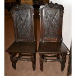 A Pair of Joined Oak Panel Back Hall Chairs, the top rails carved as two seated dogs above lozenge