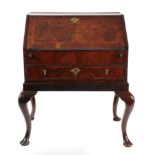 A George II Figured Walnut and Feather Branded Bureau, the fall enclosing a fitted interior of