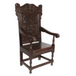 A Joined Oak Wainscot Armchair, the scrolled top rail decorated with serpents above a moulded carved