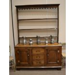 A George III Oak Enclosed Dresser and Rack, with a wavy shaped apron above three fixed shelves,