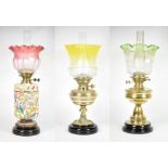 Three oil lamps, with coloured glass shades