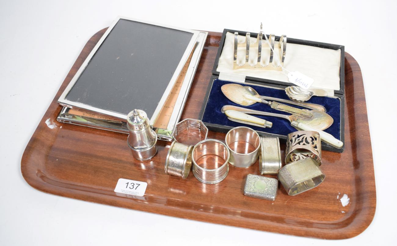 A group of assorted silver items to include: two photograph frames; various napkin rings; a toast