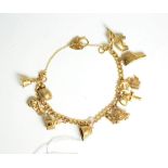 A 9 carat gold charm bracelet, hung with ten charms including an elephant, a rugby ball, a helmet