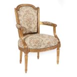 ~ A Louis XVI Style Carved Giltwood Fauteuil, mid 19th century, upholstered in close-nailed floral