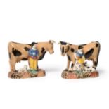 A Pair of Yorkshire Pratt Type Pottery Cow Groups, circa 1810, the standing beasts with buff and