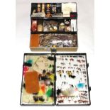A plastic cantilevered tackle box containing an assortment of fly tying equipment and accessories,