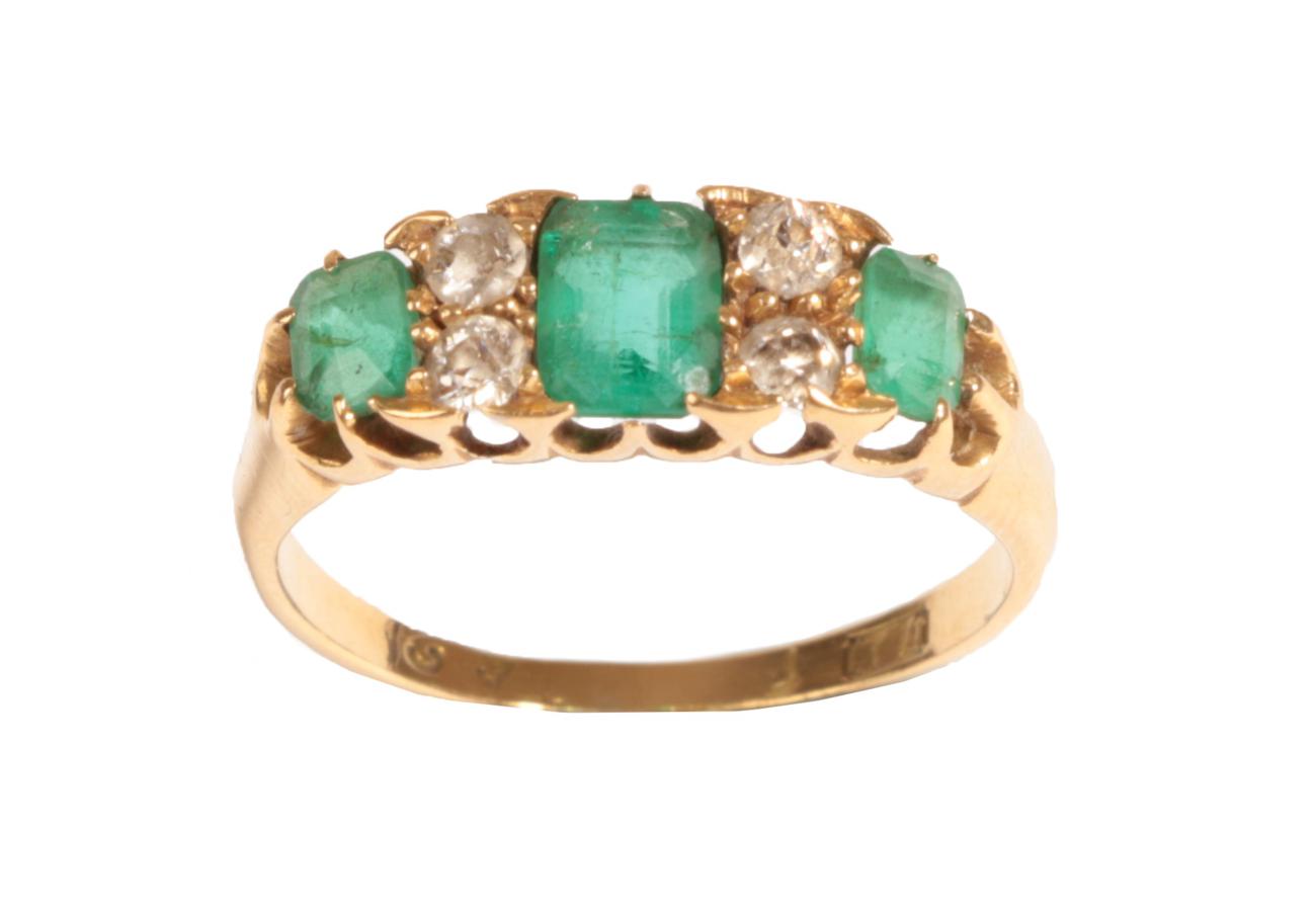 An Emerald and Diamond Ring, the graduated emerald-cut emeralds alternate with pairs of old cut