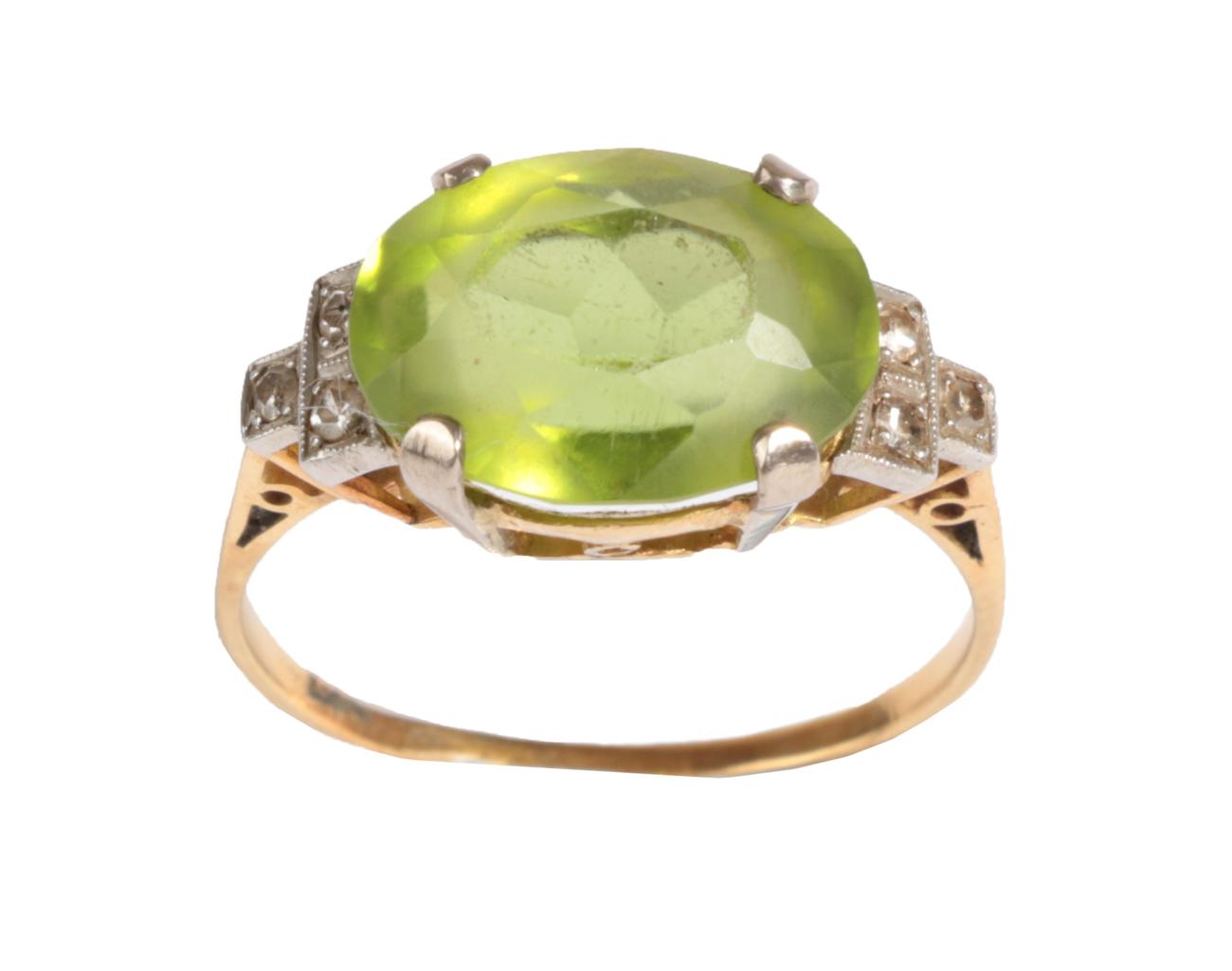 A Peridot and Diamond Ring, circa 1930, the oval cut peridot to shoulders each set with three single