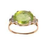 A Peridot and Diamond Ring, circa 1930, the oval cut peridot to shoulders each set with three single