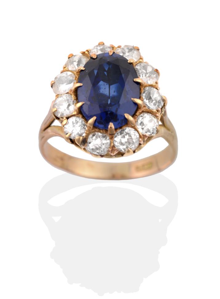 A Synthetic Sapphire and Diamond Cluster Ring, an oval cut synthetic sapphire in a claw setting,