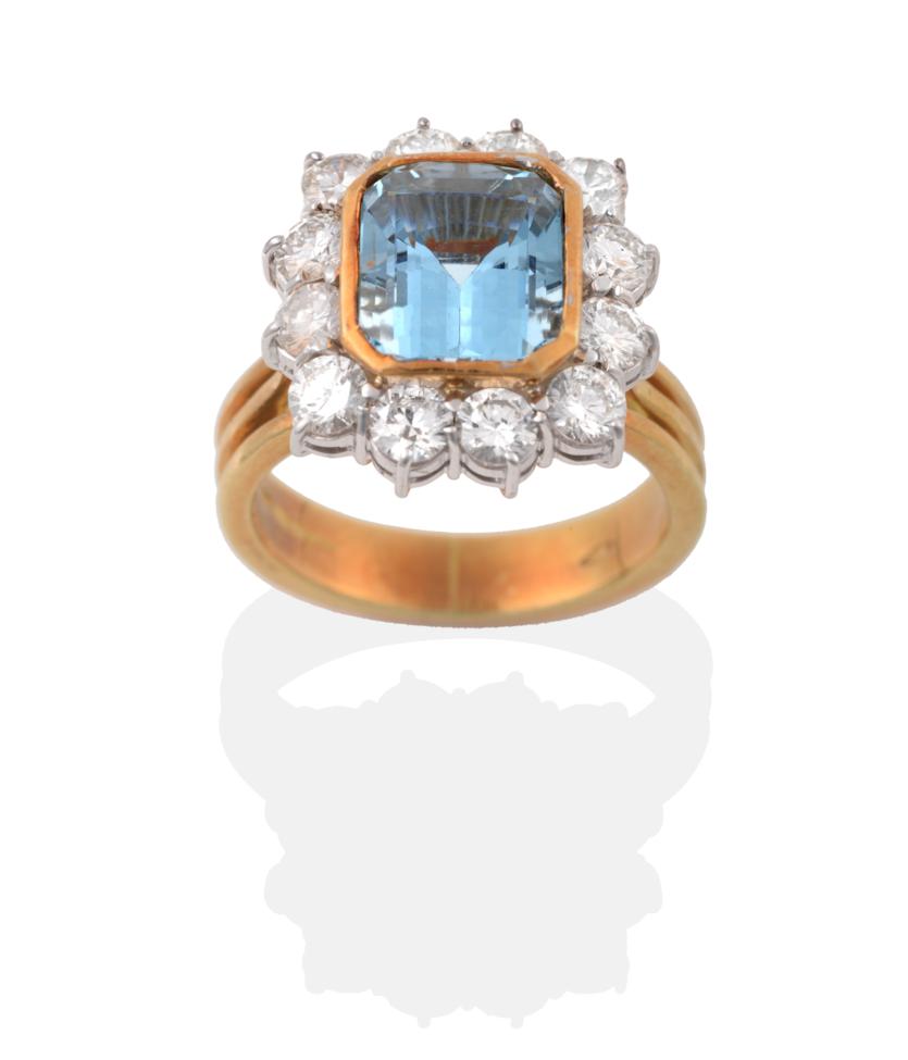 An 18 Carat Gold Aquamarine and Diamond Cluster Ring, an emerald cut aquamarine in a yellow rubbed