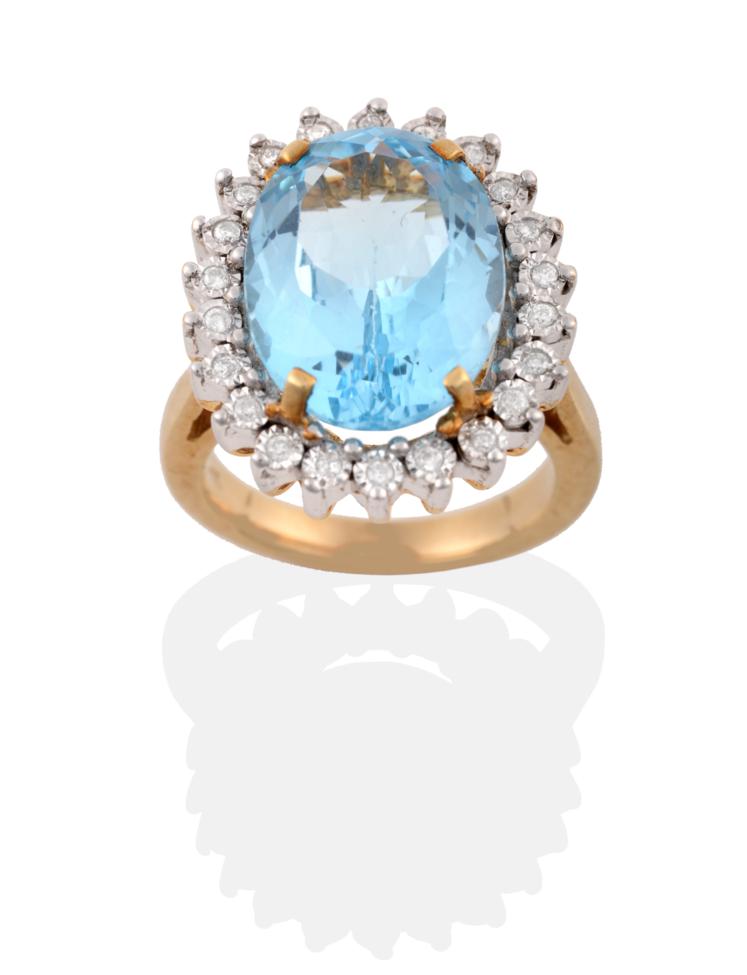 A 9 Carat Gold Blue Topaz and Diamond Cluster Ring, an oval cut topaz in a yellow four claw setting,