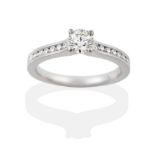 A Platinum Diamond Ring, the round brilliant cut diamond in a four claw setting, to shoulders