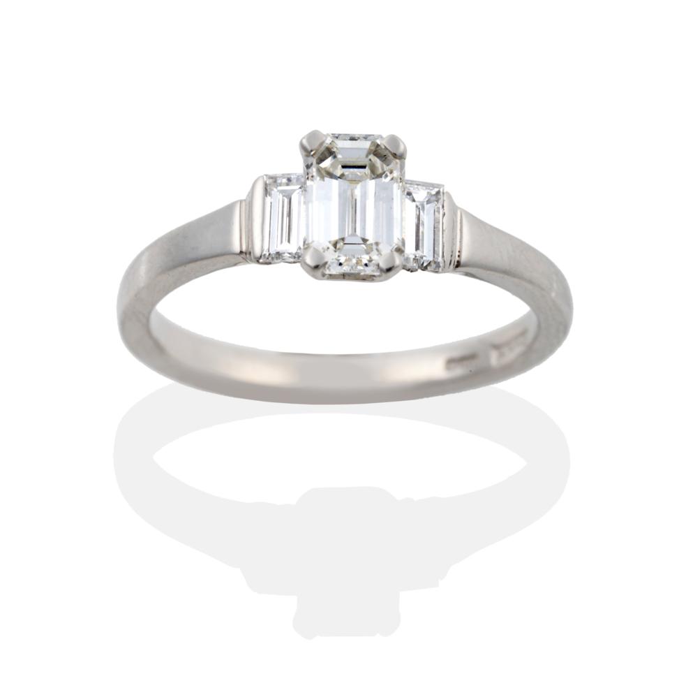 A Platinum Diamond Three Stone Ring, a central emerald-cut diamond in a four claw setting, flanked