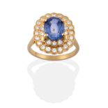A Sapphire and Diamond Cluster Ring, an oval mixed cut sapphire in a yellow four claw setting,