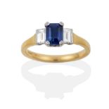 An 18 Carat Gold Sapphire and Diamond Three Stone Ring, the octagonal step cut sapphire flanked by a