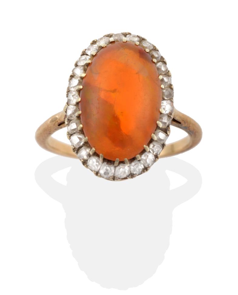 A Fire Opal and Diamond Cluster Ring, an oval cabochon fire opal within a border of old cut diamonds