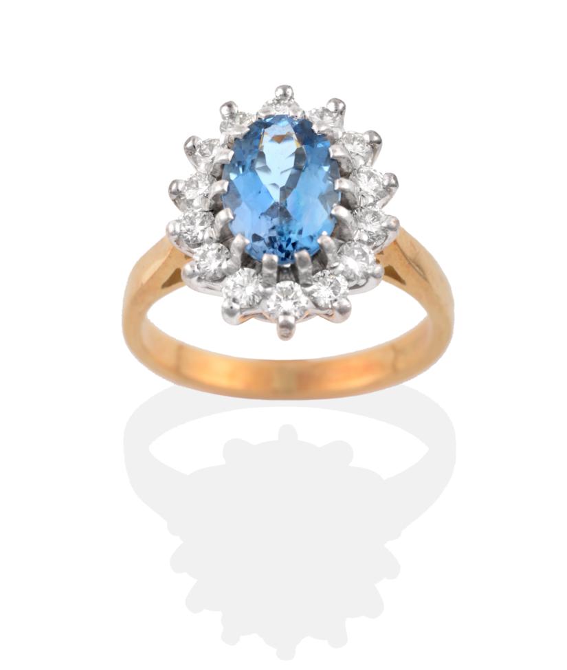 An 18 Carat Gold Aquamarine and Diamond Cluster Ring, an oval cut aquamarine within a border of