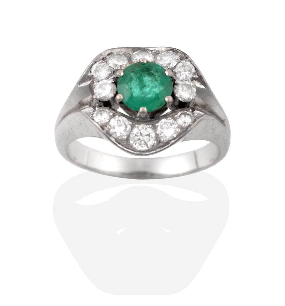 A Contemporary Emerald and Diamond Cluster Ring, a round cut emerald flanked by two round