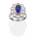A Platinum Sapphire and Diamond Cluster Ring, the oval mixed cut sapphire in a rubbed over setting