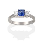 A Platinum Sapphire and Diamond Three Stone Ring, the square octagonal step cut sapphire between two