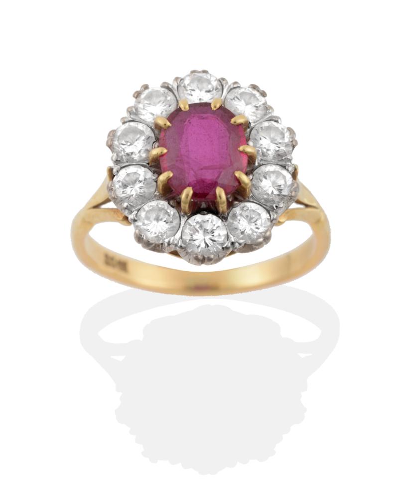 A Ruby and Diamond Cluster Ring, an oval cut ruby in yellow claw settings, within a border of