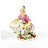 A Chelsea Porcelain Figural Sweetmeat Dish, circa 1755, as a seated Turk holding a shell, on a mound