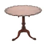 A Carved Mahogany Tripod Table, in George III style, the fliptop with a carved C scroll border, on a