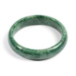 A Jade Bangle, of varied green tones, inner diameter 6.5cm Provenance: Purchased by the vendor's