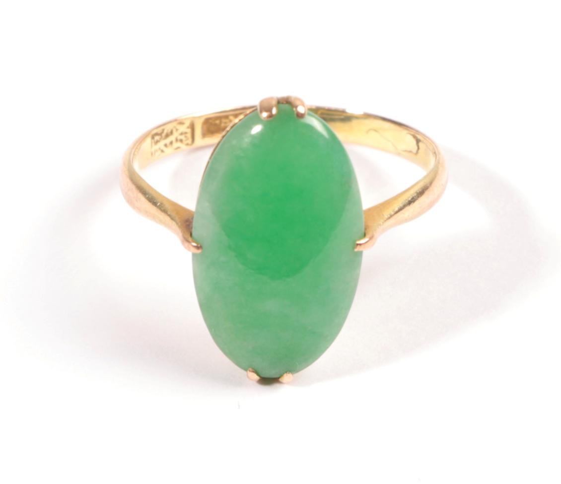A Jade Ring, the oval cabochon held in yellow claw, to a tapered shoulder plain polished shank,