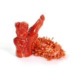 A Chinese Coral Carving of a Boy, standing beside a tree stump, 7cm high; and A Coral Necklace, 36cm