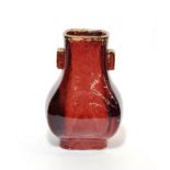 A Chinese sang de boeuf twin handled faceted baluster vase on rectangular footed base