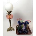 A quantity of coloured glassware including vases and an oil lamp with pink glass reservoir