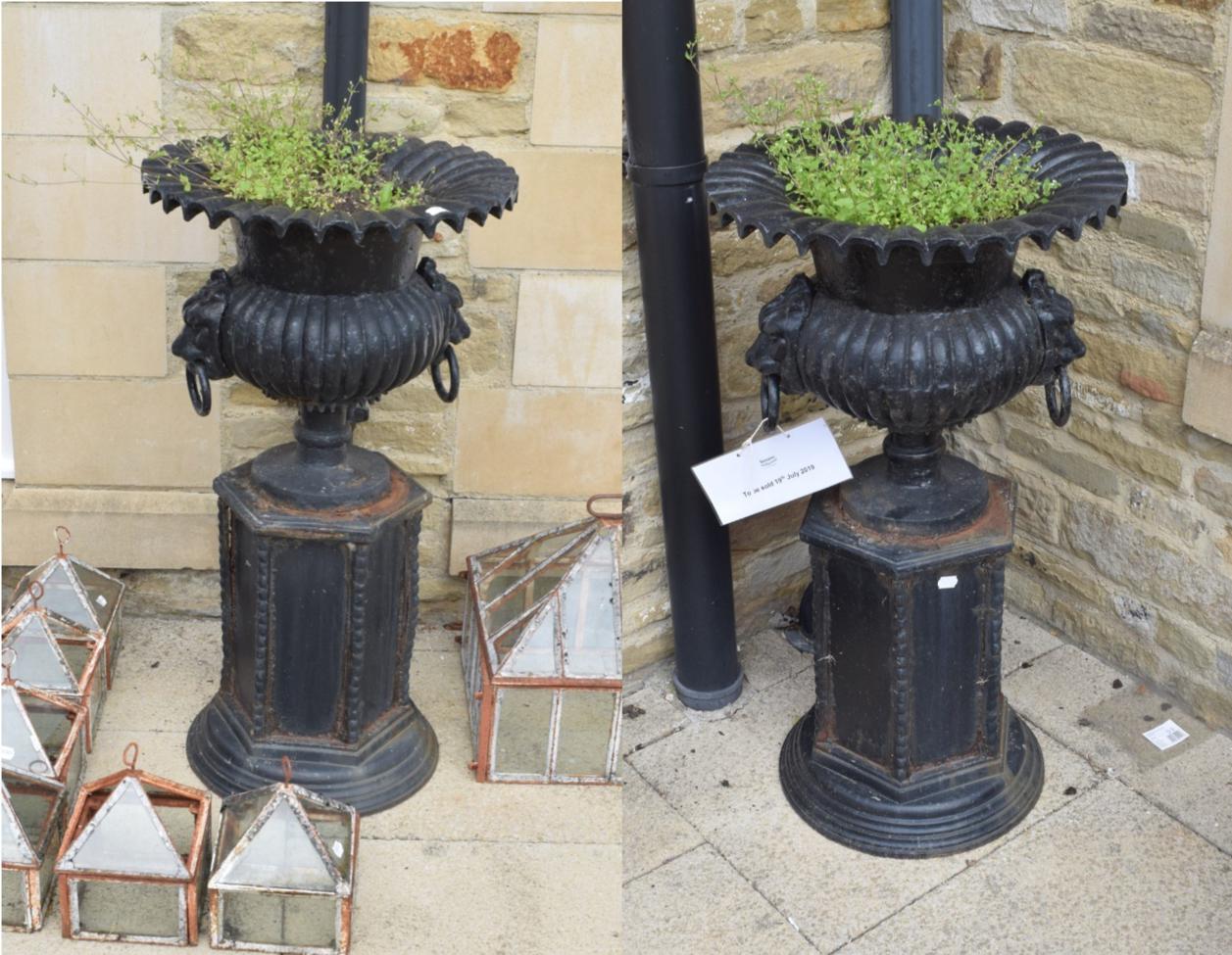 ^ A pair of cast iron campana shaped garden urns, with lion mask handles, standing on a plinth