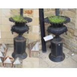^ A pair of cast iron campana shaped garden urns, with lion mask handles, standing on a plinth