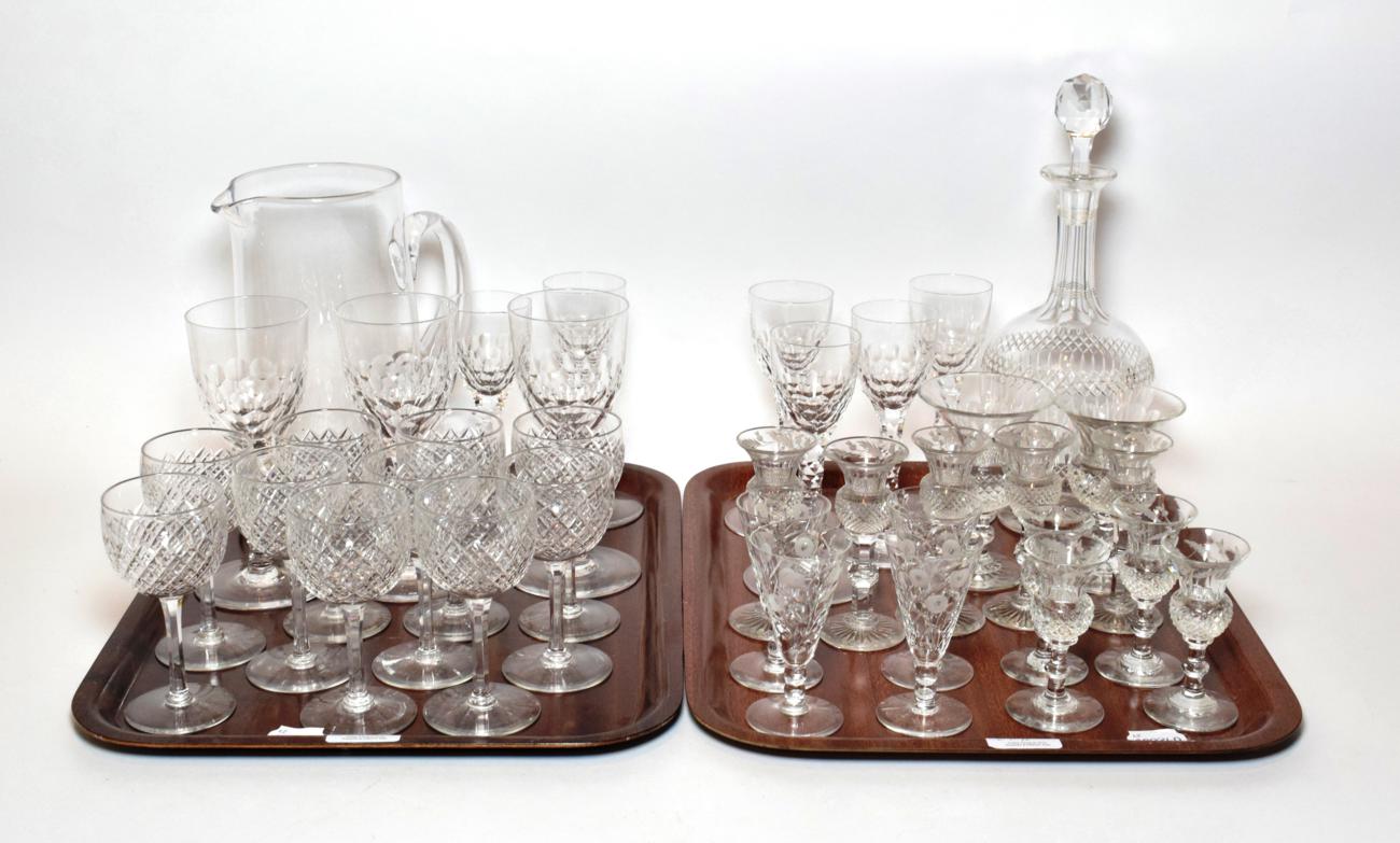 Two trays of drinking glasses including thistle form glasses, jug, decanter etc