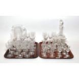 Two trays of drinking glasses including thistle form glasses, jug, decanter etc