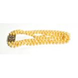 A three row cultured pearl choker, with ruby set square snap stamped '9CT', length 35cm. Gross