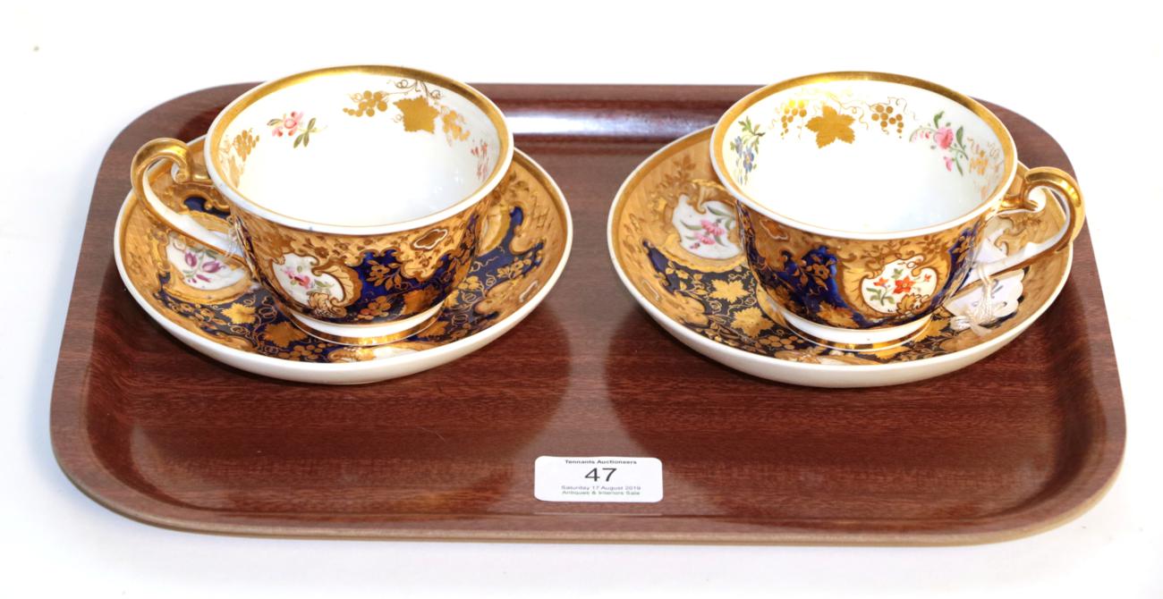 A pair of Ridgeways tea cups and saucers, floral decorated and gilt highlighted on a cobalt blue